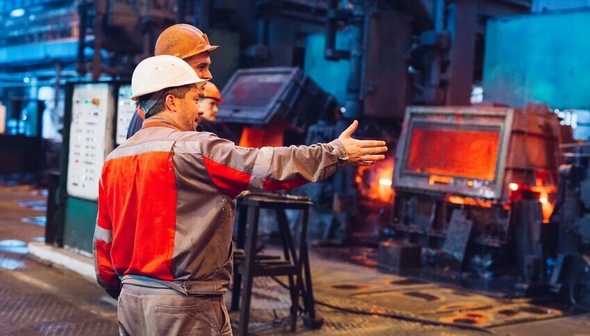 Steel workers communicate in a factory.