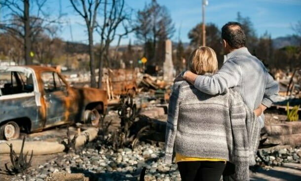 couple looking at destroyed house after natural disaster