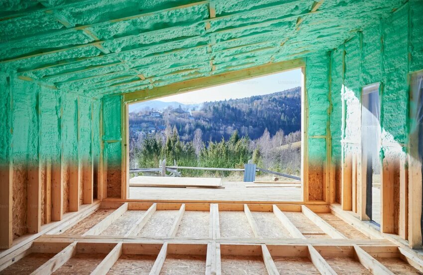 a view of the mountains through the open frame of a home being built. the foam insulation has just been applied to the walls.