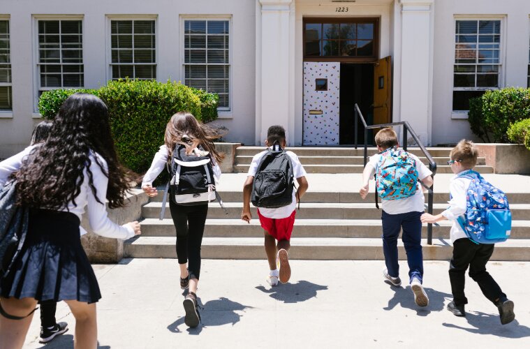 Back View Shot of Students Running into School