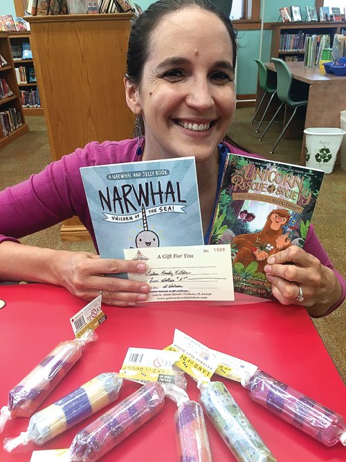 Rachel Lenstra, youth services librarian, poses with a small selection of the prizes for the Galena Public Library&rsquo;s summer reading program.