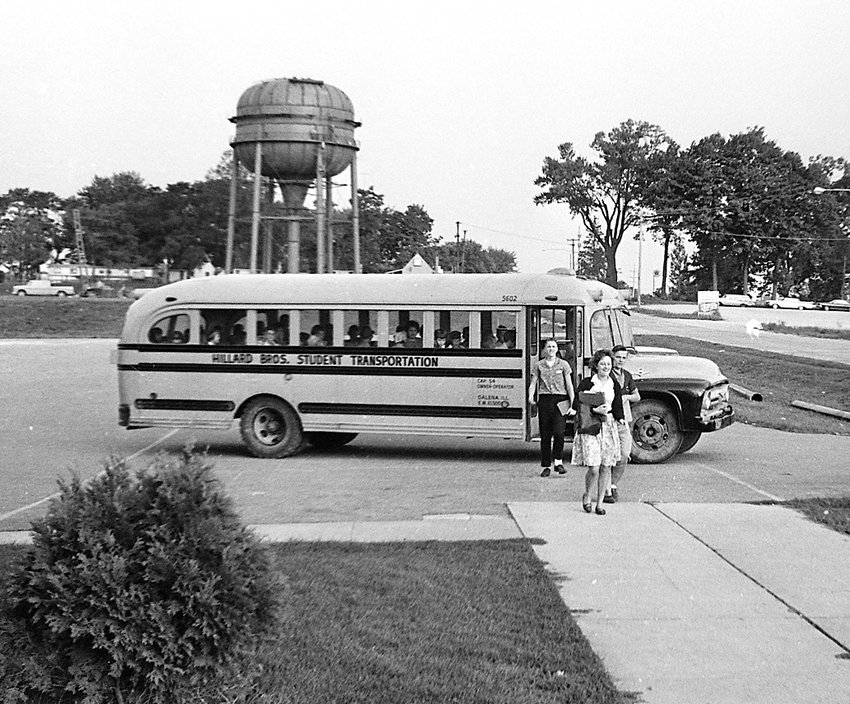 Students depart a school bus in the fall of 1963 at Galena High School. In the background, the newly-constructed Franklin Street water tower begins to take form.