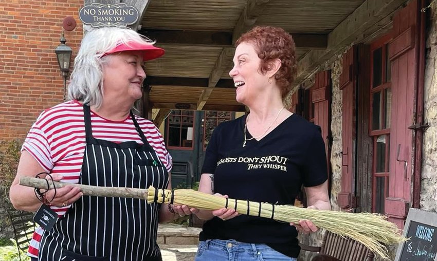 Robyn Davis (right), owner of A Darkness Lovely Boutique, presents a special hand-made cobwebber broom to Betty Roliardi (left), operator of the historic Dowling House Tours.