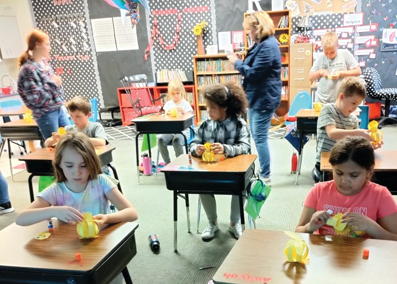 Standing, FFA member Cora Ritchie, left, and third-grade teacher Deb Reese watch the progress of students working on their project including, back from left, Rylee Hendrickson and Emmett Patterson; middle, from left, Ayden Chambers, Tyra Banks, Joshua Radick; and front, from left, Julia Gerlich and Aaliyah Easter.