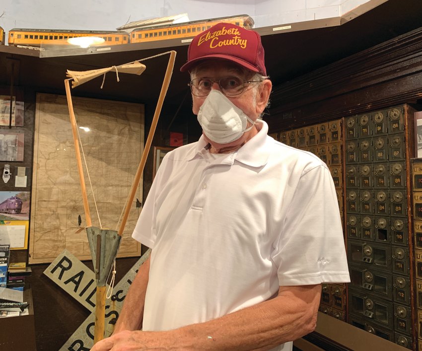 Gerald Speer, curator of the Elizabeth Railroad Depot Museum,  holding a message hoop.  One can see mail boxes where mail from trains was inserted.