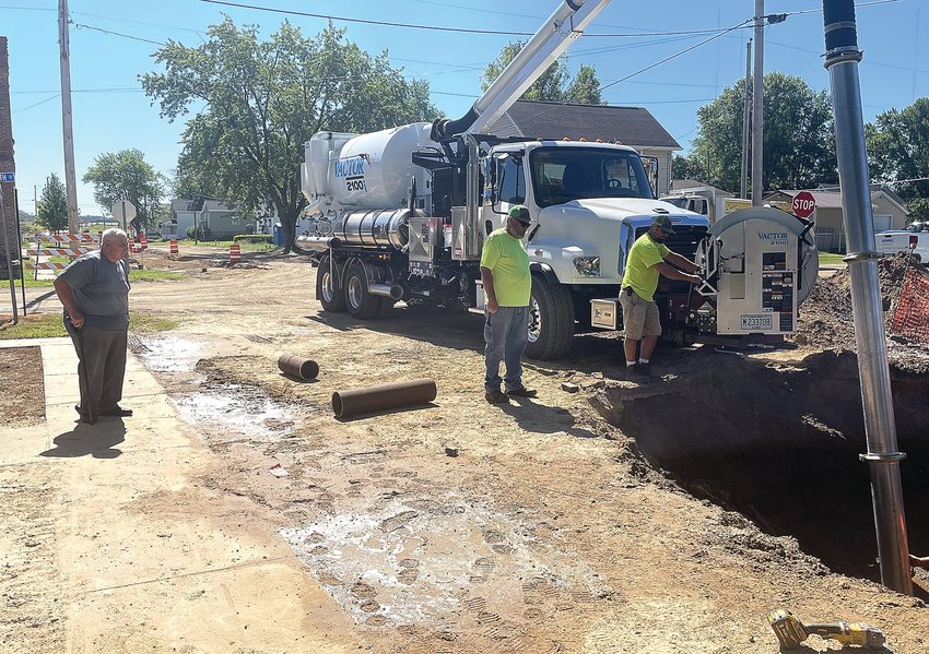 East Dubuque Mayor Randy Degenhardt, left, watches as Tom Burns and Tony VanOstrand, right, clear water and mud with the Vactor sewer cleaner so a crew can repair a water main break.