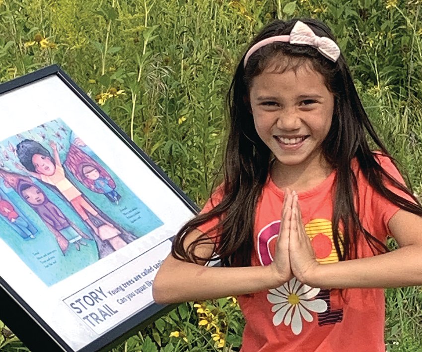 Alexa Martinez Vazquez, 8, a Galena Primary School third grader, soaks in the words and actions represented in the story boards for Call Me Tree/Ll&aacute;mame &aacute;rbol and then jumps high as a tree.