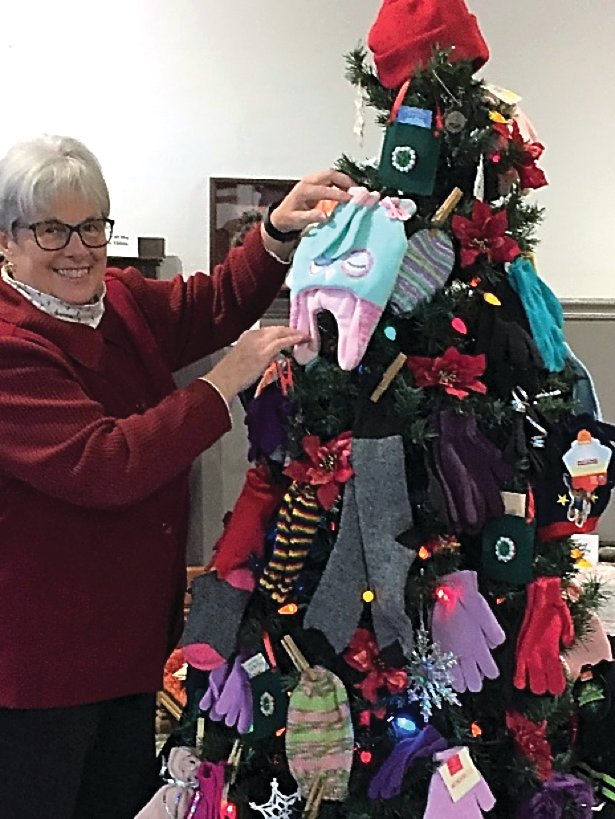 Ann Coppernoll, Stockton, of the Woodbine Unit, decorates the holiday tree at Stockton Heritage Museum with winter items.