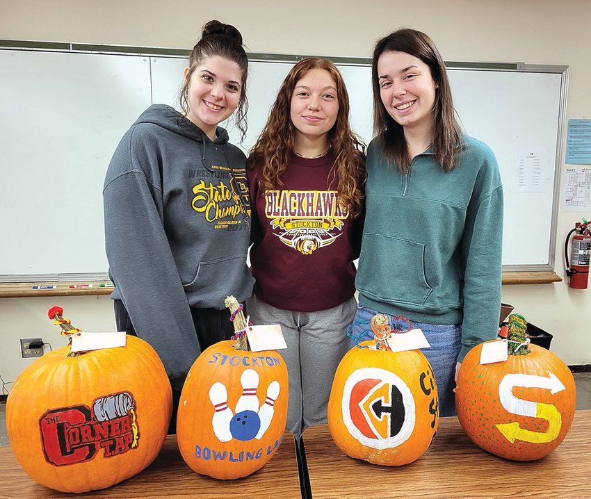 Students in Stockton High School&rsquo;s business class painted logos from 17 local companies on pumpkins with a note stating, &ldquo;Thank you for being an asset to our community.&rdquo; Inspecting four of the pumpkins are, from left, Olivia Keeffer, Ella Wackerlin and Maddie Harbach. Business instructor Lindsey Duerr noted, &ldquo;My students had a great time doing this project and the businesses really enjoyed them.&rdquo;