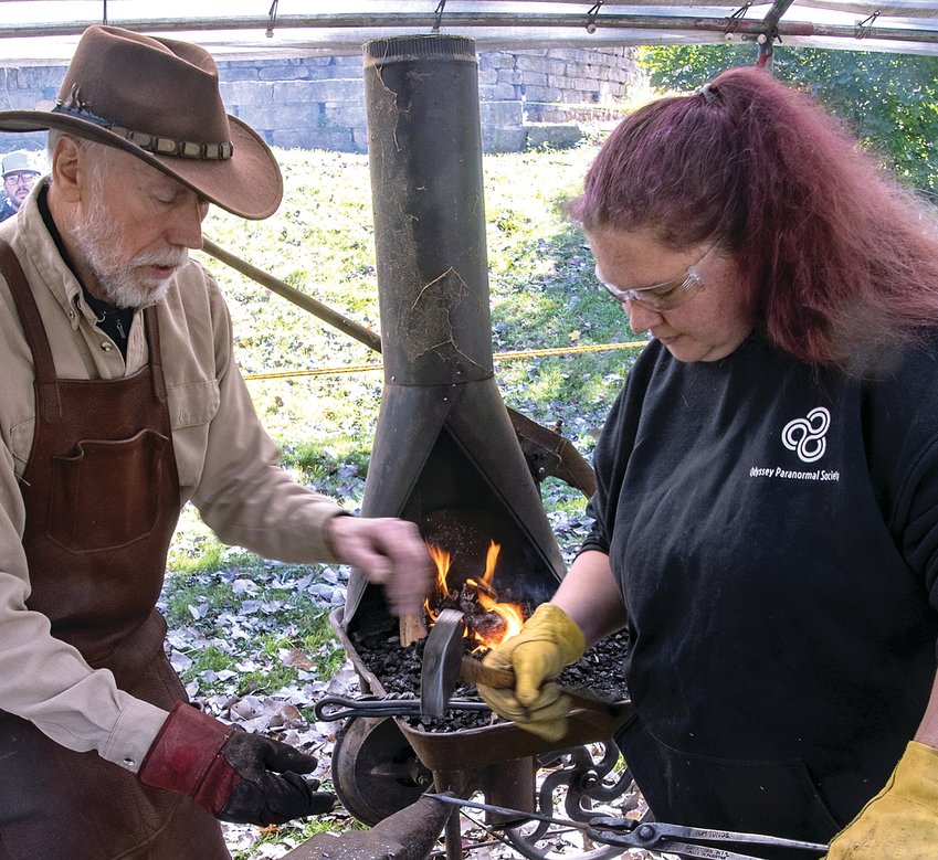 Tom Lobacz, volunteer at Galena&rsquo;s Old Blacksmith Shop, demonstrates the Sears Acme forge to Debra Krabbnenhoff, Chadwick.