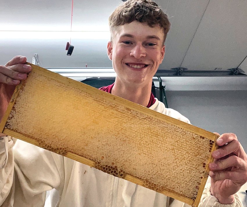 Chase Dittmar shows off one of his frames filled with wax combs.