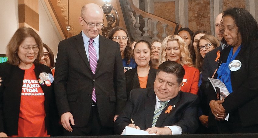 Gov. JB Pritzker signs a bill banning the sale and manufacture of assault weapons and high-capacity magazines on the Senate floor Monday.