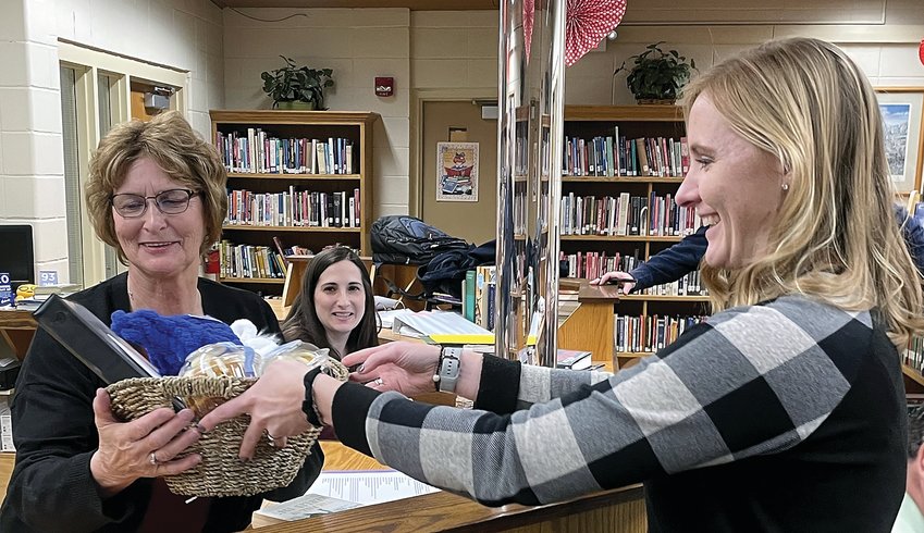 Patti Murphy, left, receives a gift basket including a manual on how to be retired from Arlee Stodden, Galena School Board president at the board&rsquo;s, Monday, Jan. 23 meeting. Watching the events unfold is Anne Heim, Murphy&rsquo;s replacement.
