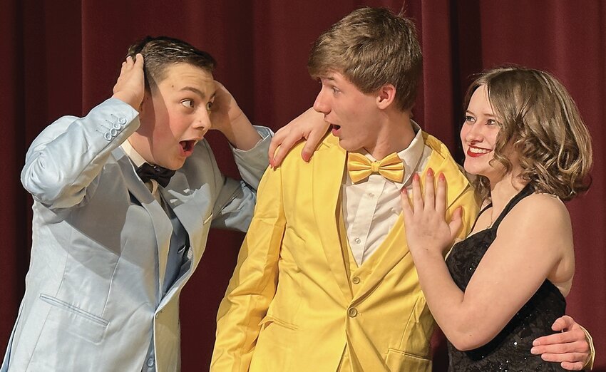 Everett Noble (left), as Steve 2, and Conner Soat (center), as Steve 1, have their hands full as they deal with Trikva, played by Ella Getz (right), the mysterious sister of the foreign exchange student from Branstalkvania, at Millard Fillmore High School&rsquo;s Totally Rockin&rsquo; 80&rsquo;s Prom. The Galena High School Drama Club will present this original immersive dinner-theatre comedy this weekend on April 20 through 22, at 6:30 p.m. at Turner Hall. Tickets are $15. Seats can be reserved with any cast or crew member or send payment via Venmo to @trulytracy, via Paypal to galena@gmail.com, or email galena@gmail.com.