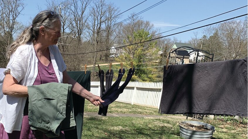 Emily Huppert gathers sun-dried clothes from her makeshift clothesline.