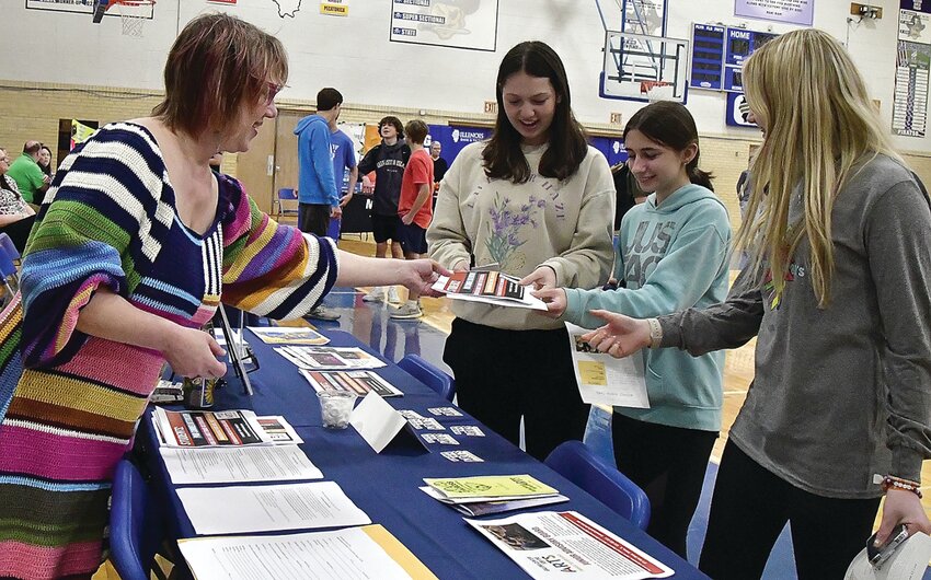 On Thursday, April 20 in the Galena High School gymnasium, the Galena Area Chamber of Commerce hosted a job fair. For the first two hours, the job fair was open only to high school students, but the last three hours, it was open to the public. 17 businesses participated, bringing along information and applications for open positions. The businesses that attended were Apple Canyon Lake, Galena Territory Association, City of Galena, Jo-Carroll Energy, Chestnut Mountain Resort, Keller Williams-The Danielle Cline Group, Eagle Ridge Resort and Spa, Kreider Services, Fried Green Tomatoes, Mediacom, Furst Staffing, Midwest Senior Care Center, Galena Cellars Winery and Vineyard, Riverview Center, Galena Center for the Arts, The Country Experience, and The Workshop. Here, Stephanie Beck, representing the Galena Center for the Arts, passed out internship information to high schoolers Kallan Kropp, Dani Rae Hulscher and Xela Weber.