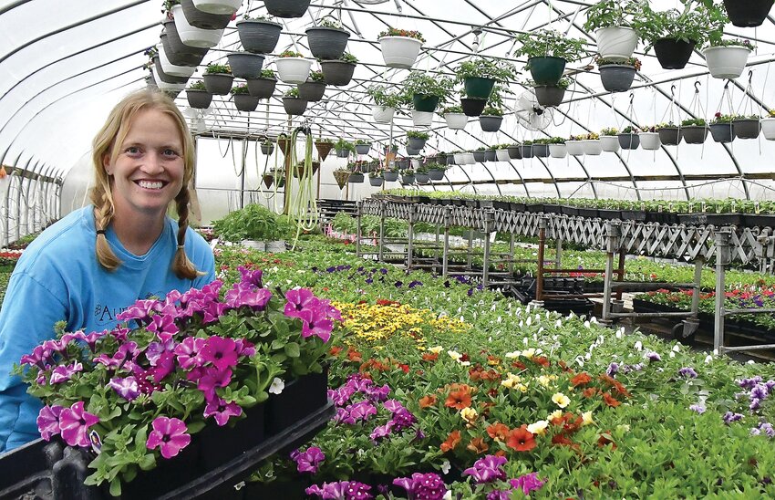 Aunt Beez Greenhouse owner Bridget Zurcher poses in one of her greenhouses surrounded by fresh flowers available for purchase.