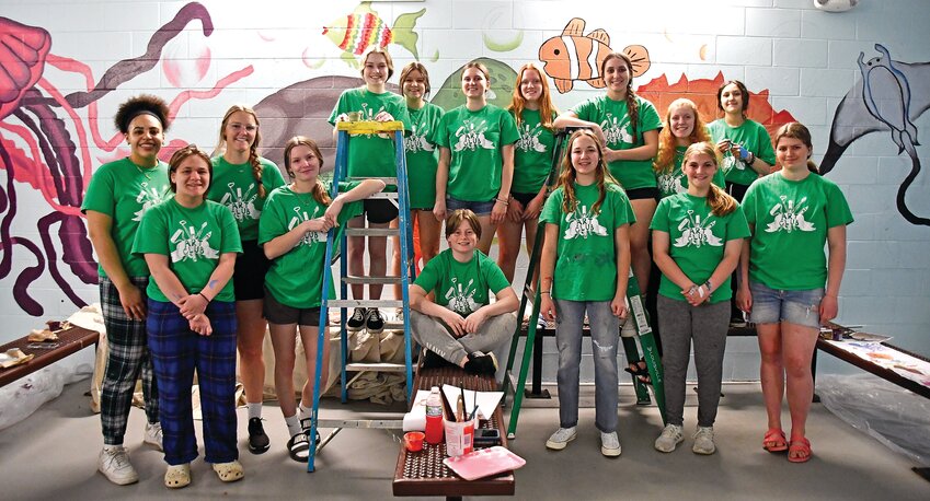 Students from Scales Mound stand by their mostly-completed mural in the men&rsquo;s locker room at Galena&rsquo;s Alice T. Virtue Memorial Pool. Front row: Carley Weis, Mickayla Bass, Katherine Bilderback, Rori Distler, Anika Stadel and Zoie Koehler. Back row: Sydney Driscoll, Garrett Pickel, Denali Fenn, Daphne Havens, Grace Behlke, Alyssa Wentz, Amanda Withington, Anna Wentz, Olivia Elizabeth Havens. Not pictured: Lila Anderson.