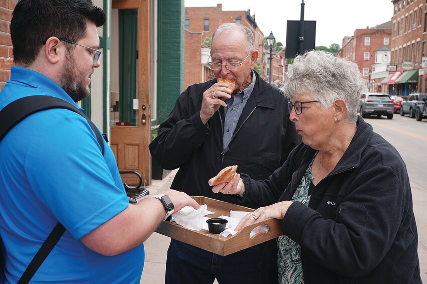 Devin Ganka of Galena Food Adventures, left, offers empanadas from Galena Bakehouse to Gary and Connie Landon from Lancaster, Wis.