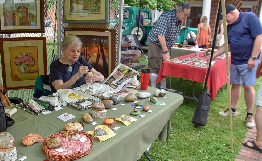 Jacquie Dyrke, in the foreground, demonstrates her painting; Larry Cording, in the background, explaining his woodturning techniques during last year&rsquo;s festival.