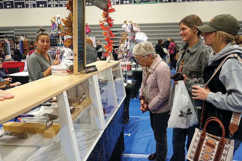 A representative of A Fudge Lovin&rsquo; Company, right, tempts (L-R) Margi Mapes and her granddaughters Cierra and Cheyenne Mapes with some fudge treats at the River Ridge Craft Show Sunday, October 8. The Craft Show was put on by the River Ridge PTO at the RR high school. PTO president Jessica Engle said the show, now in its 29th year, featured arts and crafts from 84 vendors this year.