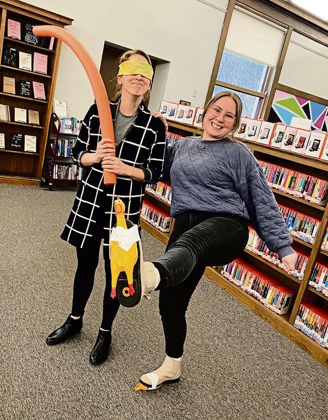 Jenna Diedrich, left, library director, and Sam DuHack, right, circulation services librarian, model the gear for &ldquo;Keep Your Chicken Quiet,&rdquo; a teen game to be held at the Galena Public Library on Wednesday, March 27 at 5pm.