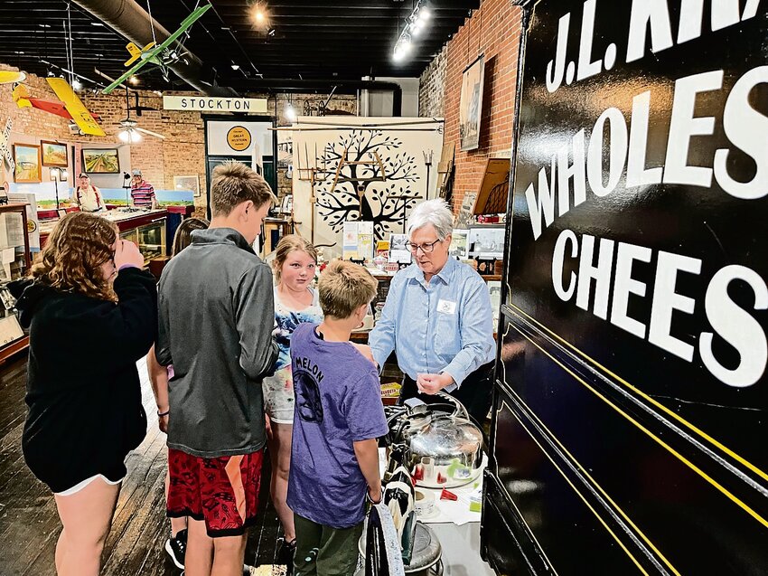 Museum board member and host Ann Coppernoll shares information about the history of the Kraft cheese plant in Stockton and demonstrates a milking machine to sixth grade Stockton elementary students.
