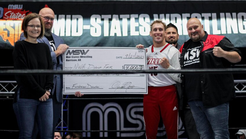 Northwest Arkansas District Fair Manager Allison Black (left) is presented a check for $4,0000 by Mid-States Wrestlers 