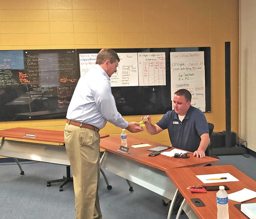 Harrison School Superintendent Dr. Stewart Pratt holds a marker for board member Nate Wilson to draw and determine the length of his board term.