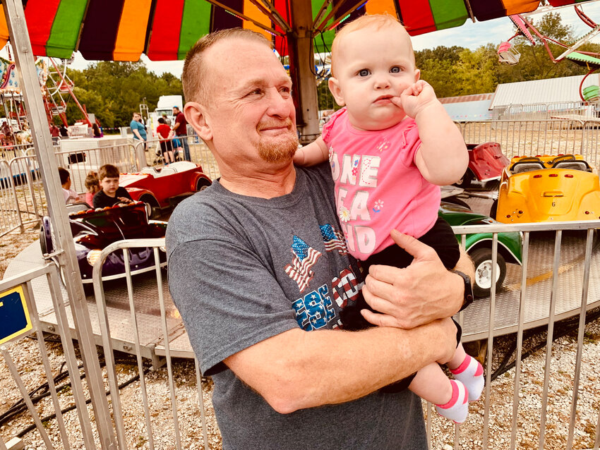Rosalee Luper (age 11 months) enjoys the sights and sounds during opening night of the Carnival at the Northwest Arkansas District Fair on Wednesday night at fairgrounds in Harrison. Rosalee is held by Donnie Phillips. The District Fair will continue through Saturday night, with the Carnival open through Saturday night and the Demolition Derby event on Saturday night.