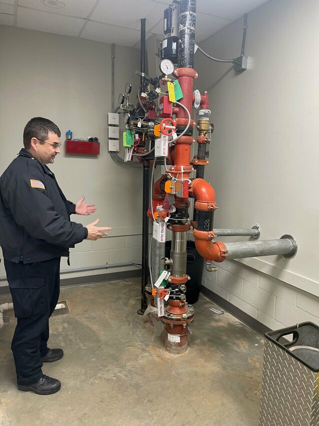 Fire Chief Marc Lowery shows the fire riser system that supports the sprinklers at City Hall. CONTRIBUTED PHOTO / DONNA BRAYMER