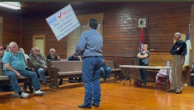 Bruce Emerson, of Pyatt, holds up a sign displaying opposition to Ozark Mountain School District's milage referendum in next Tuesday's school election. He addressed a group of 45 people meeting last Tuesday night at the Eros Community Building about the referendum seeking the 30-year continuation of 11.5 mills of bonded debt.