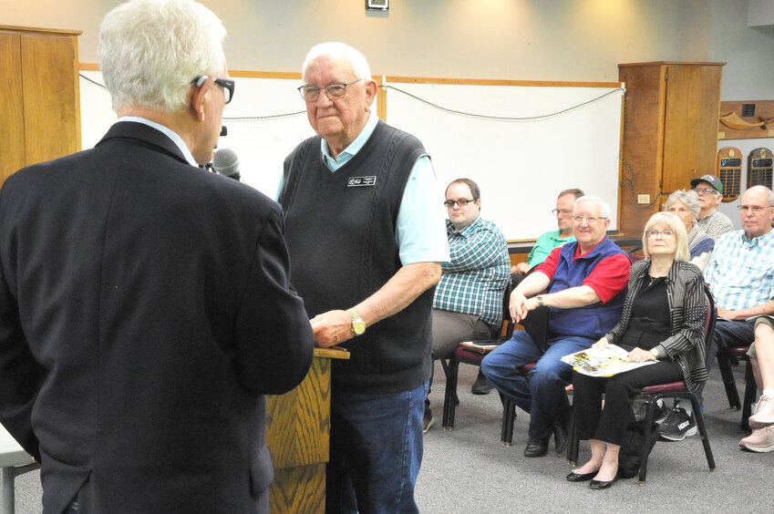 Board president Gary Belair extols Larry Brocaw’s long-time volunteer service after presenting an award to the outgoing Architectural Control Committee chair at the May board meeting. (Lewis Delavan photo)