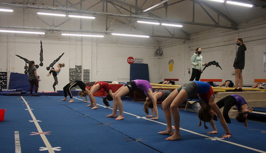 Hilltop Elite Academy of Tumbling and Trampoline, Inc., has been able to reintroduce their athletes back into the gym with COVID-19 safety precautions in place. Above, junior coaches Summer Spencer (masked, left) and Amya Greenwood (masked, right) lead stretching in the mid-level (advanced beginner to novice levels) class while Hannah Huber coaches an athlete on the trampoline in the background.