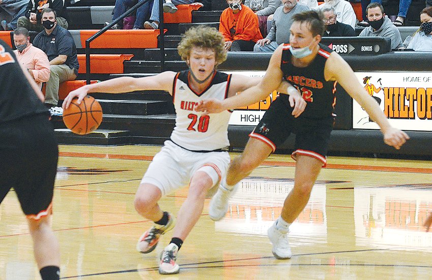 Hillsboro&rsquo;s Drake Vogel (#20) tries to drive past Will Jenkins of Lincolnwood during the county rivalry match-up on Tuesday, Dec. 7. Vogel would have 20 points in the game to help the Toppers to a 69-53 win over the Lancers.