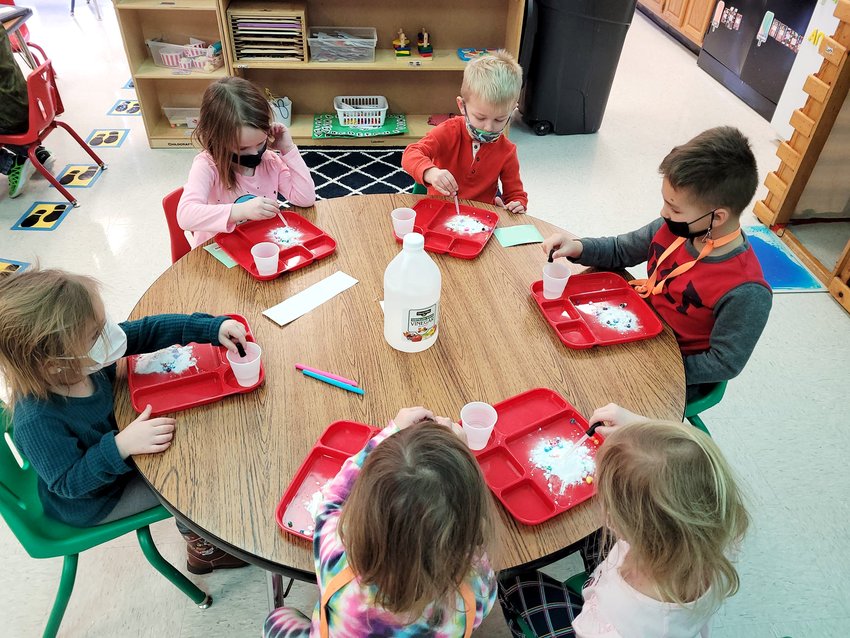 Students in the Hillsboro pre-Kindergarten program use eye droppers to drop vinegar onto a pile of baking soda to watch the reaction, which reveals hidden beads with various shapes, colors and letters to identify. The experiments utilizes science, literacy and fine motor skills.