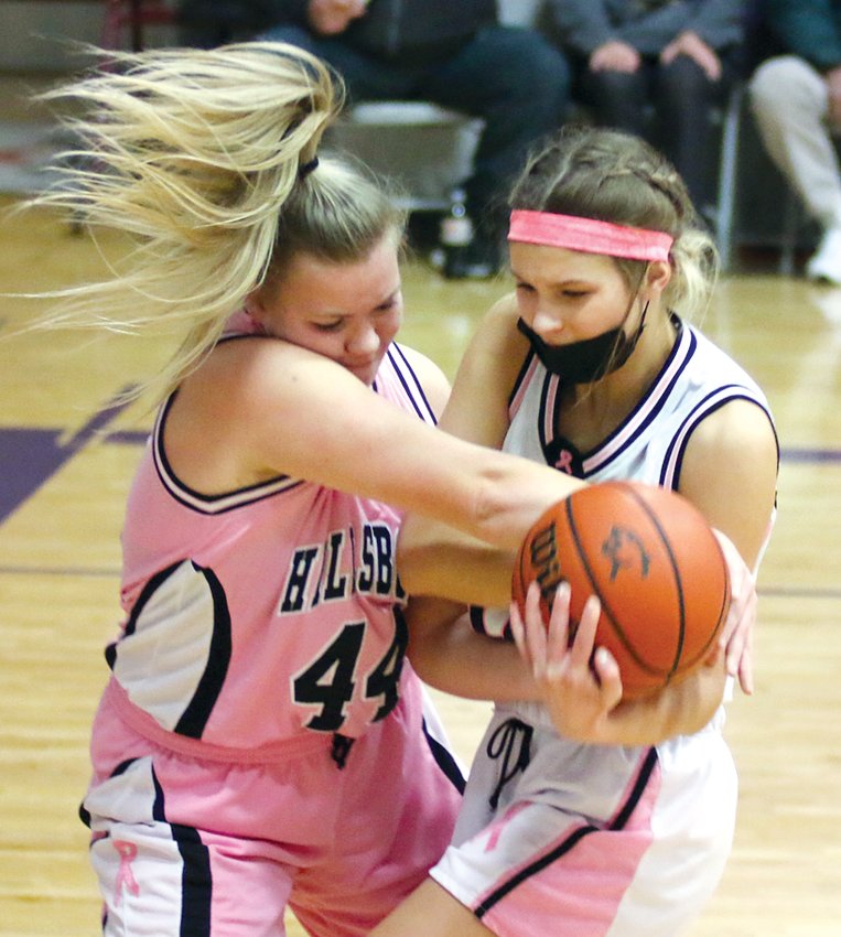 Hillsboro's Meagan White (left) and Litchfield's Lily Braasch wrestle for possession during the pink and white game at Simmons Gym on Thursday, Feb. 10. White and the Hiltoppers staked themselves to a 19-2 first quarter lead to improve to 18-8 on the season with a 51-25 victory over the Purple Panthers.