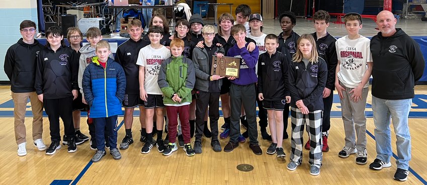 Sandwiched between their coaches, Carter Powell (far left) and Dan Newkirk (far right), the Litchfield Middle School wrestling team poses with their regional championship plaque after taking the top spot in the IESA regional tournament in Divernon on Feb. 26. The Panther Cubs had 13 sectional qualifiers on the day, with nine regional champions and two runner-up finishes.