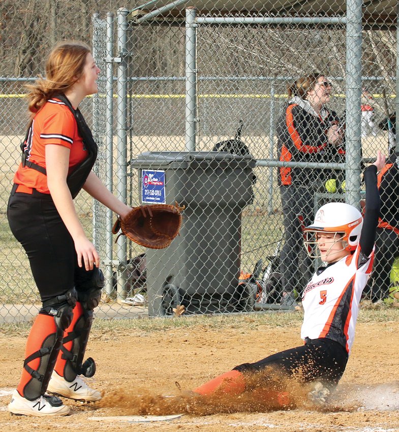 Lincolnwood senior Shelby Hattenbach slides home safely in front of Hillsboro catcher Sophia Blankenship during the Montgomery County clash on Monday, March 14. Hattenbach&rsquo;s run was the first of three for the Lancers, who defeated the Toppers 3-1 at the Hillsboro Sports Complex.