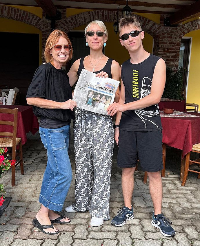Above, Melanie Sherer (left) and Laura Lauretta (center) enjoy a copy of The Journal-News, which traveled all the way to Lauretta&rsquo;s hometown in Northern Italy when the Sherers made an international trek for the high school pen pals to meet.