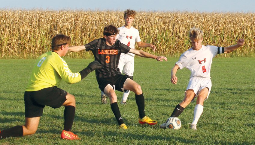 With Lincolnwood&rsquo;s Ian Keller (#3) bearing down on the ball after Mitchell Lowe&rsquo;s initial save, Addison Pollard (#9) clears away a loose ball in front of the Topper net in the second half of the county rivalry tilt in Raymond. Thanks to Lowe and the Hillsboro defense, including junior Hunter Payne (#4), the Toppers were able to hold Lincolnwood scoreless and pick up a 1-0 victory.