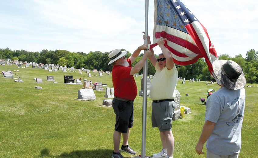From the left Brian Bevell, Kent Lovelace and Jimmy Evans raise the American flag at a special ceremony at Glendale Cemetery on Saturday afternoon, May 27. The flag was draped over the coffin of Lovelace&rsquo;s uncle, Kenneth D. Grigg, who was killed in a car crash in Florida while serving in the Reserves.