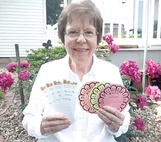 Nancy Savage of the Montgomery County Cancer Association holds up the memorial bookmarks and floral tributes that will be available at this year&rsquo;s MCCA Birthday Party and Celebration of Life.