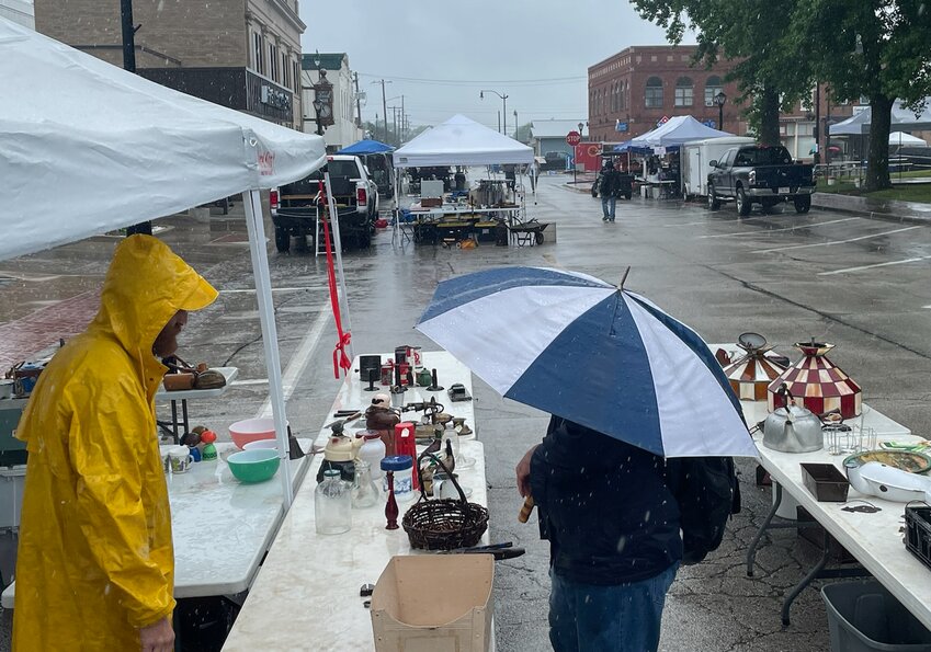 Rodney Shipman of Hillsboro, at right, buys a few items from Bob Determann of Reno, at left, during a soggy Litchfield Pickers Market on Sunday, June 11.