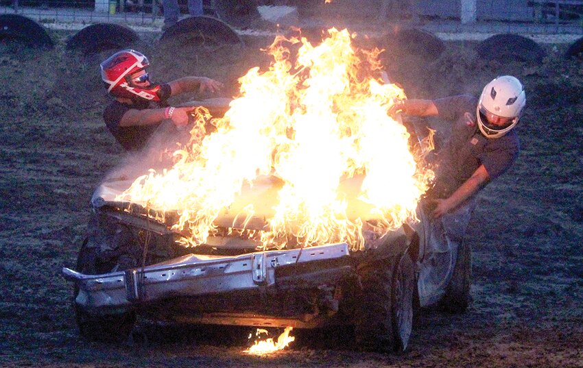 Hunter Sarver of Rosamond and his passenger bail out of their car after a fuel leak burst into flames in the bone stock compact class of the Montgomery County Fair demolition derby on Saturday, June 24, at the fairgrounds in Butler.  Volunteer firefighters from Hillsboro, Taylor Springs and Fillmore sprang into action to dowse the blaze, preventing any injures.  Fifteen vehicles competed in that class alone, as well four other classes.