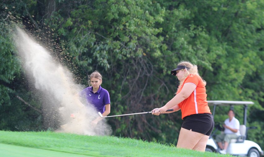 With Litchfield's Keeley Tabor looking on, Hillsboro's Sam Frailey chips out of the sand trap during the Toppers' season opener in Staunton on Tuesday, Aug. 15. Frailey shot a 53 to finish third individually behind Staunton's Breanna Feeley (48) and Lilly Bandy (49). Tabor carded a 62 in her debut, one of four Litchfield players playing their first varsity match.