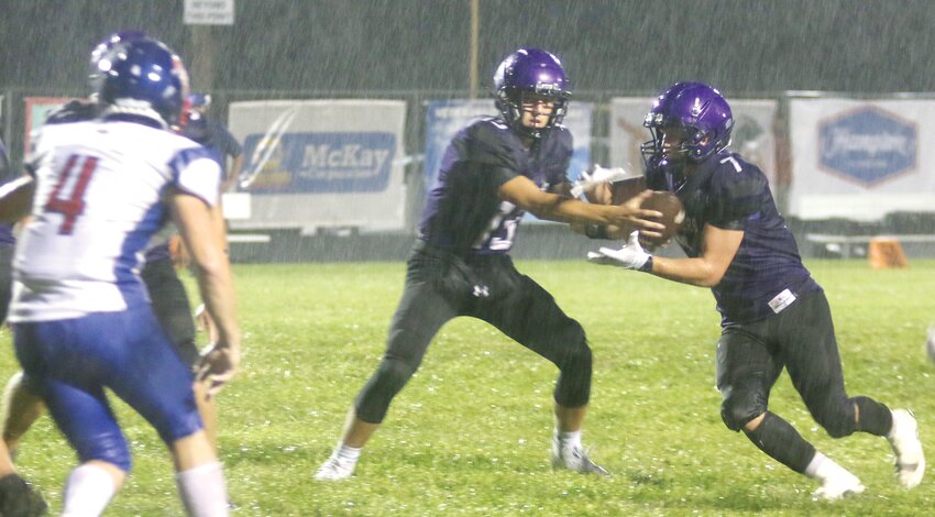 Litchfield senior A.J. Sypherd takes the handoff from quarterback Tate Dobrinich in the pouring rain during the second quarter of the Panthers' season opener against Carlinville on Saturday, August 26. Sypherd's run didn't stop until he hit the end zone as he scored the first of Litchfield's two touchdowns in a competitive 35-14 loss to the Cavaliers.