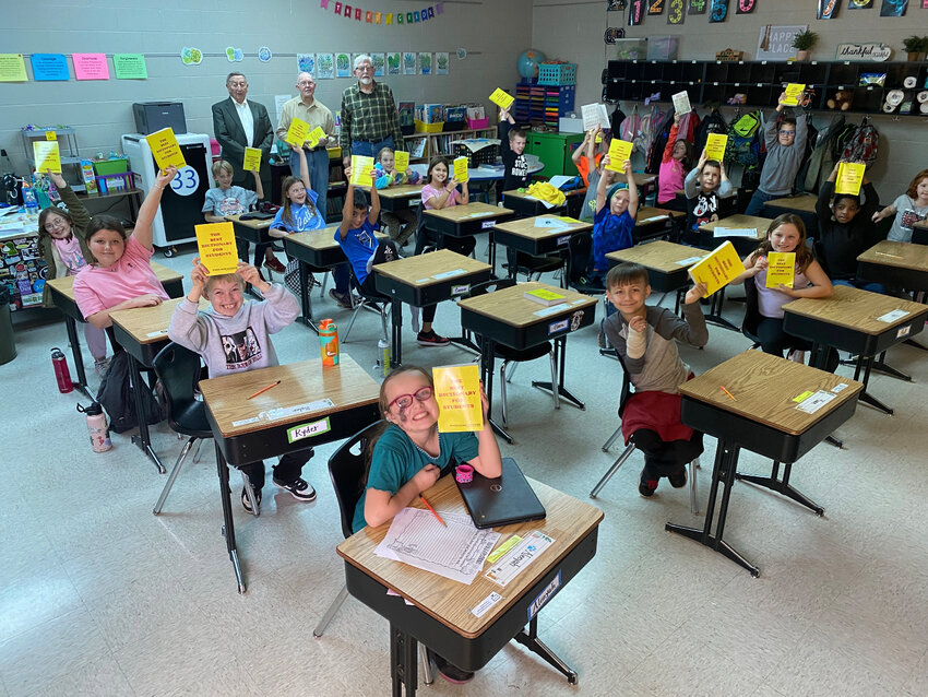 Pictured above, students in Mrs. Hoffman&rsquo;s third grade class hold up their brand new dictionaries. In the rear of the classroom are Rotarians, from the left, Tom Gooding, Jerry Wesley and Jack Evans.