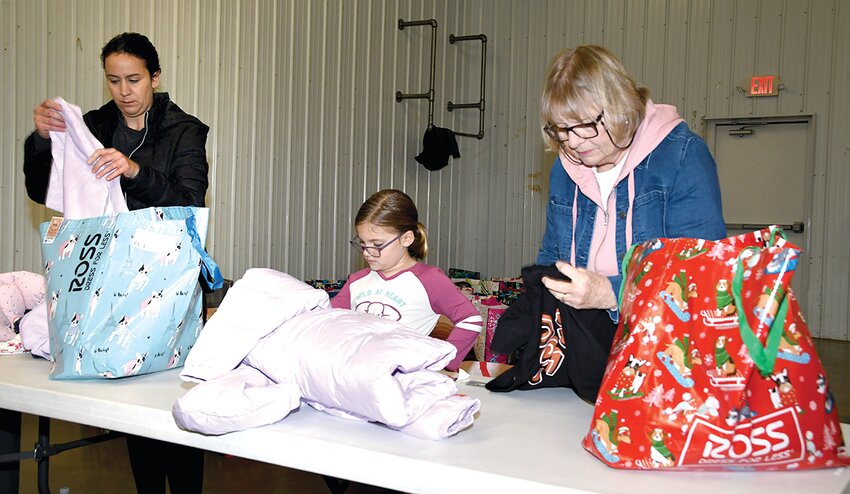 Local volunteers, from the left, Noelle and Hailey Black and Carol Sneed sort and pack bags on Saturday, Nov. 4, at The Next Network in Litchfield as part of this year&rsquo;s Coats for Kids program.