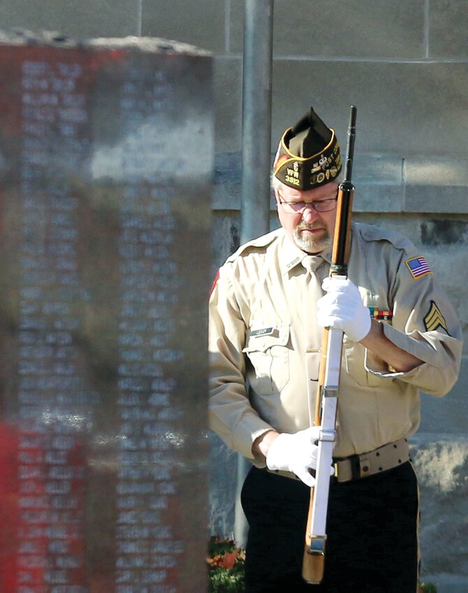 With the Litchfield Veterans Memorial in the foreground, Dennis Lewey of the VFW 3912 color guard stands at attention after the gun salute to end the Veterans Day ceremony in Litchfield on Saturday, Nov. 11.